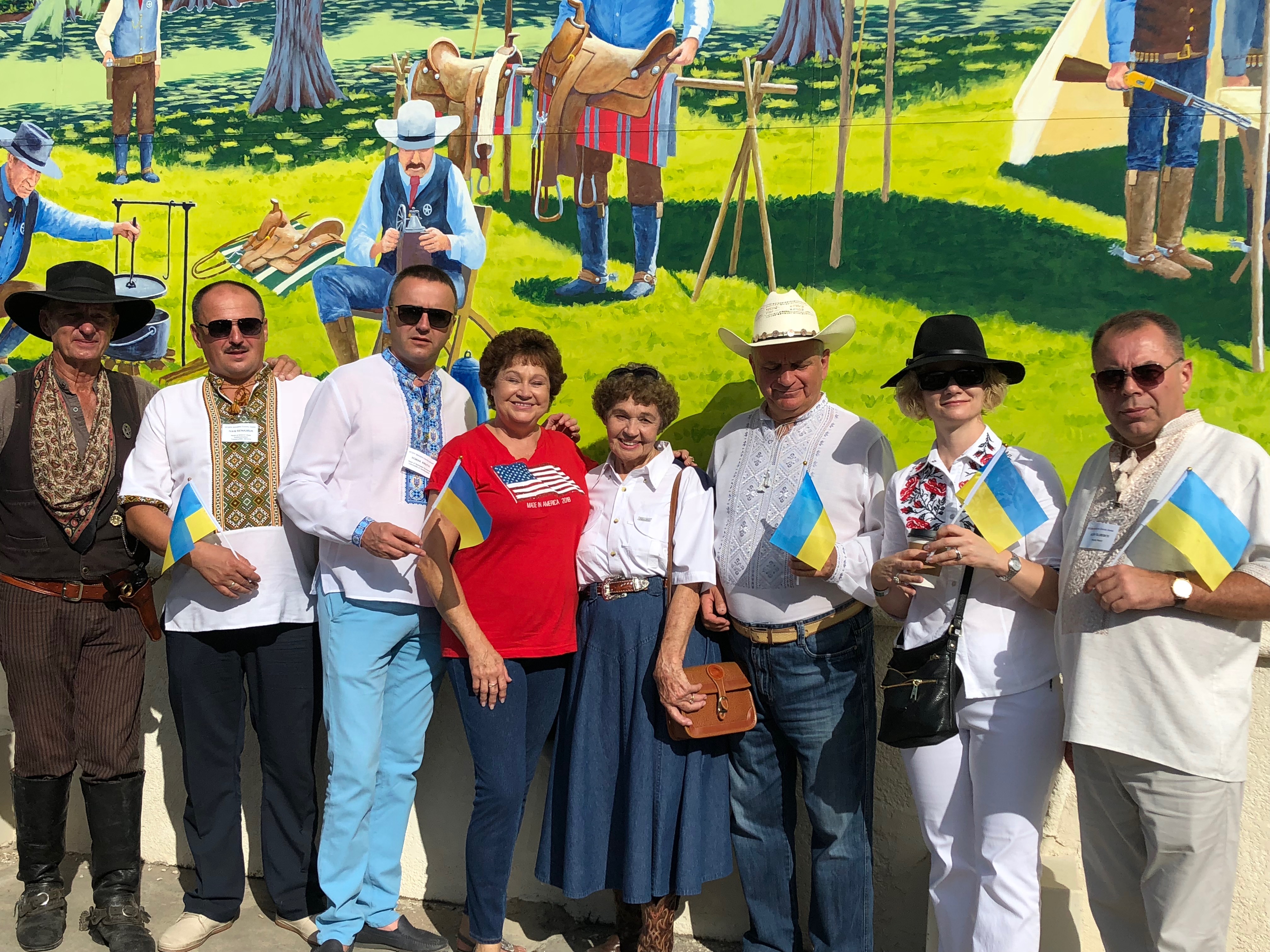 Delegation and volunteers pose in front of a mural
